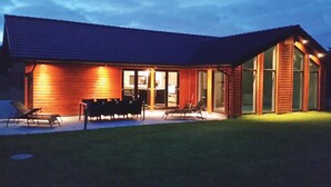 A house with a covered patio, a dining area with chairs, and a large sliding glass door leading to an interior space. - Lovely home in Ebeltoft with sauna (Ebeltoft)