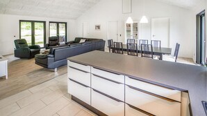 A modern kitchen with a large island, a dining area with a long table and chairs, and a living area with a sofa and chairs. - Lovely home in Ebeltoft with sauna (Ebeltoft)