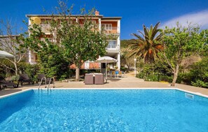 Relax by the pool surrounded by lush greenery and palm trees.