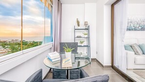 A balcony with a glass table, two chairs, a bookshelf, and a sofa. - Beach front apartment in Mijas Costa (Mijas Costa)