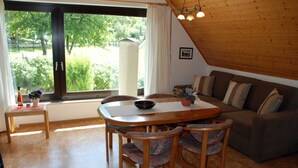 Una sala de estar acogedora con una mesa de comedor de madera, sillas y un sofá.