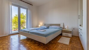 Una camera da letto con un letto grande, un comodino, una cassettiera e vista su un balcone.