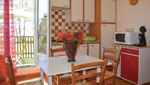 A compact kitchen with a dining table, chairs, a microwave, and a coffee maker.