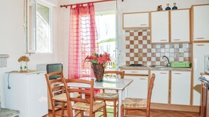 A compact kitchen with a dining table, chairs, a small refrigerator, and a sink.