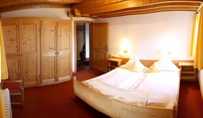 A wooden bedroom with a bed, bedside tables, and a wardrobe. - Apartment Rierk - Gästehaus Schiffmann (Tegernsee)