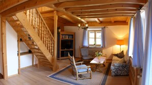 Un interior de madera con una escalera, un sofá, una mesa y una estantería.