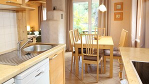Cucina con lavello, lavastoviglie, tavolo di legno e sedie.