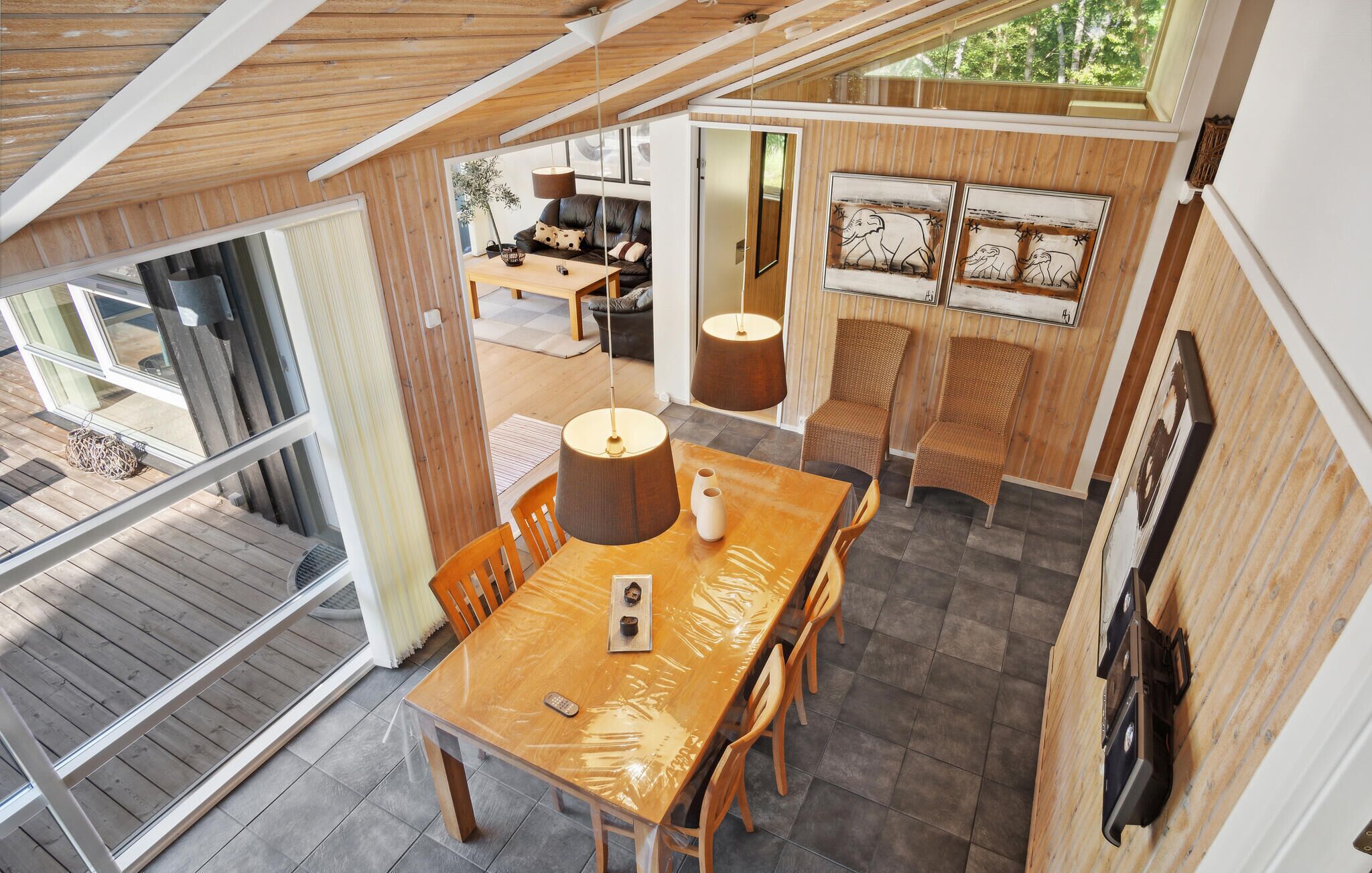 Un grand espace à manger avec une table et des chaises en bois, une cuisine à l’arrière-plan et une vue sur l’extérieur.