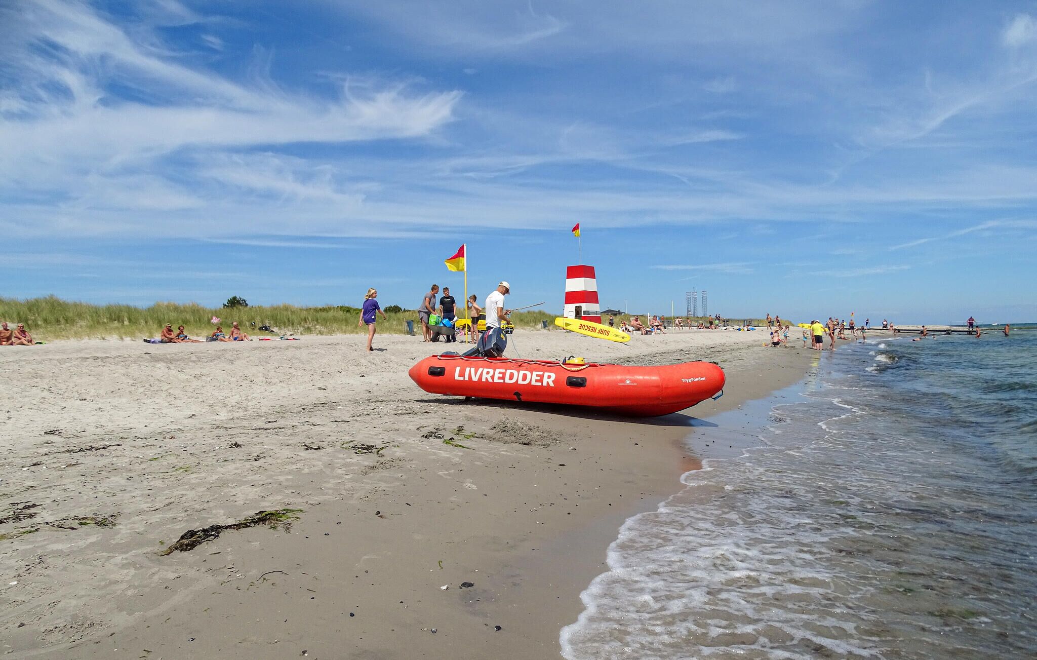 Een reddingsboot op een zandstrand, met mensen op de achtergrond.