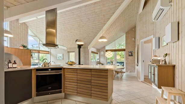 A modern kitchen with a central island, built-in oven, and wooden cabinetry. - Beautiful home in Ebeltoft with WiFi (Ebeltoft)