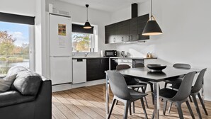 Moderni keittiö, jossa on ruokailutila sekä sisäänrakennettu uuni, mikroaaltouuni ja vedenkeitin.