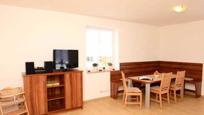 Ein gemütlicher Wohnraum mit einer Holzeinrichtungsanlage, einem Fernseher, einem Esstisch mit Stühlen und einem Fenster mit Aussicht.