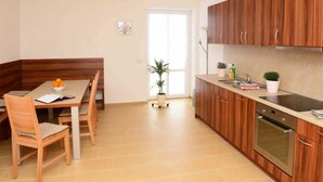 Eine moderne Küche mit Holzausstattung, einem eingebauten Backofen und einem Essbereich mit Tisch und Stühlen.