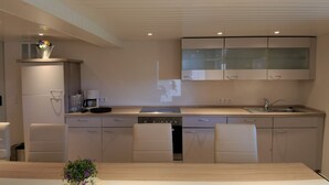 Una cocina moderna con armarios blancos, lavavajillas integrado y una isla grande con fregadero.