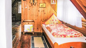 Ein Zimmer mit Holzboden, einem Bett, einem Nachttisch, einer Lampe und einem kleinen Tisch.