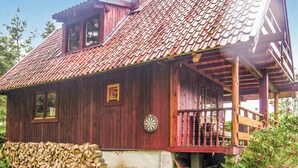Ein Holzhaus mit rotem Ziegeldach, einer Holzveranda und einem kleinen Fenster.