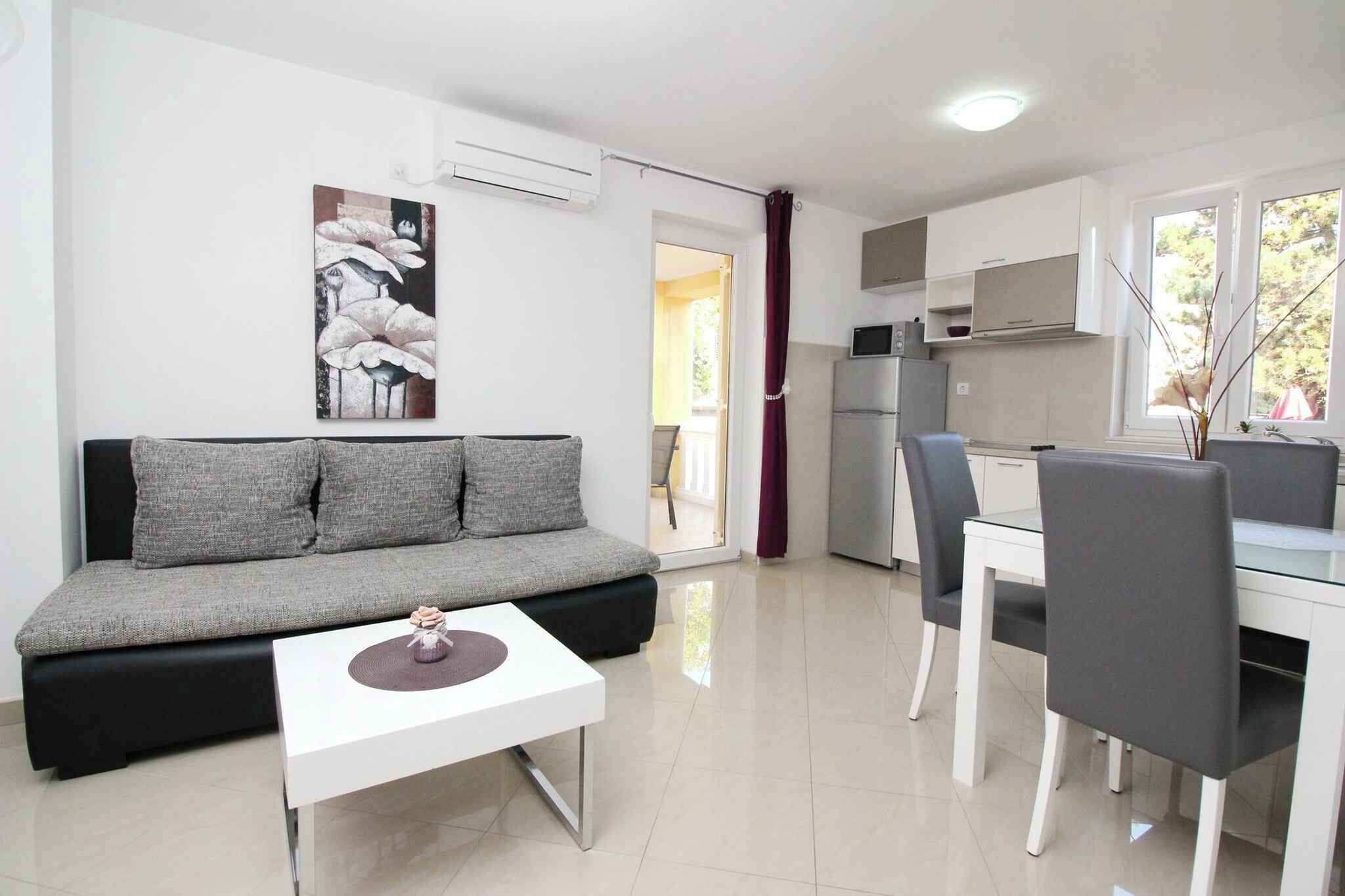 Un soggiorno moderno con un divano grigio, un tavolino da caffè bianco e una zona pranzo con tavolo e sedie grigie.