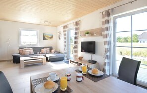Una sala de estar moderna con sofá, mesa de centro y comedor con alimentos para el desayuno.