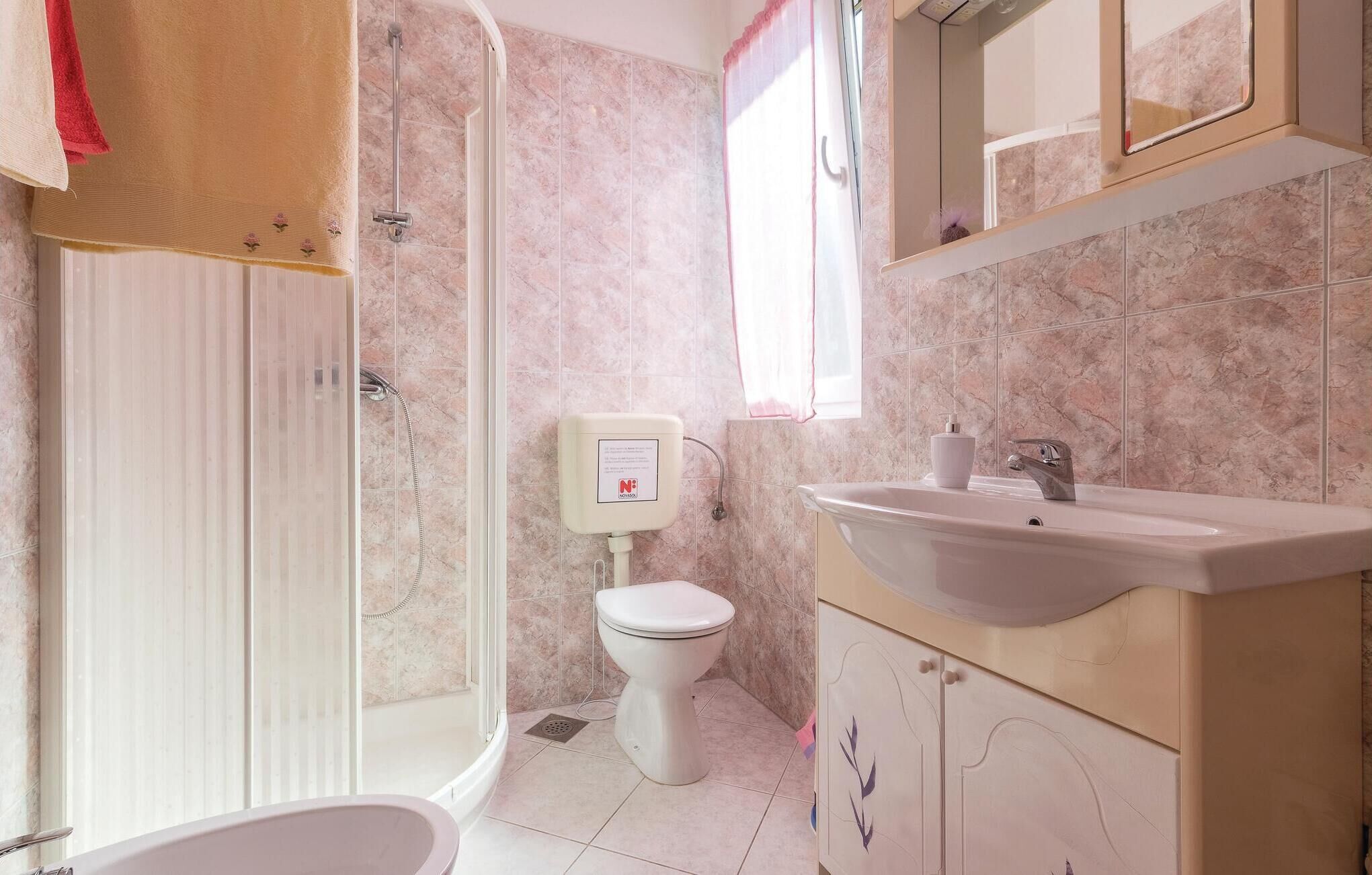 Un bagno con doccia, WC, lavandino e specchio.