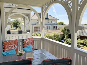 A covered outdoor seating area with a table, chairs, and a view of neighboring houses.