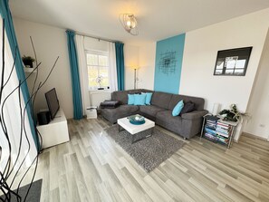 A modern living room with a grey sofa, a white coffee table, and a blue accent wall.