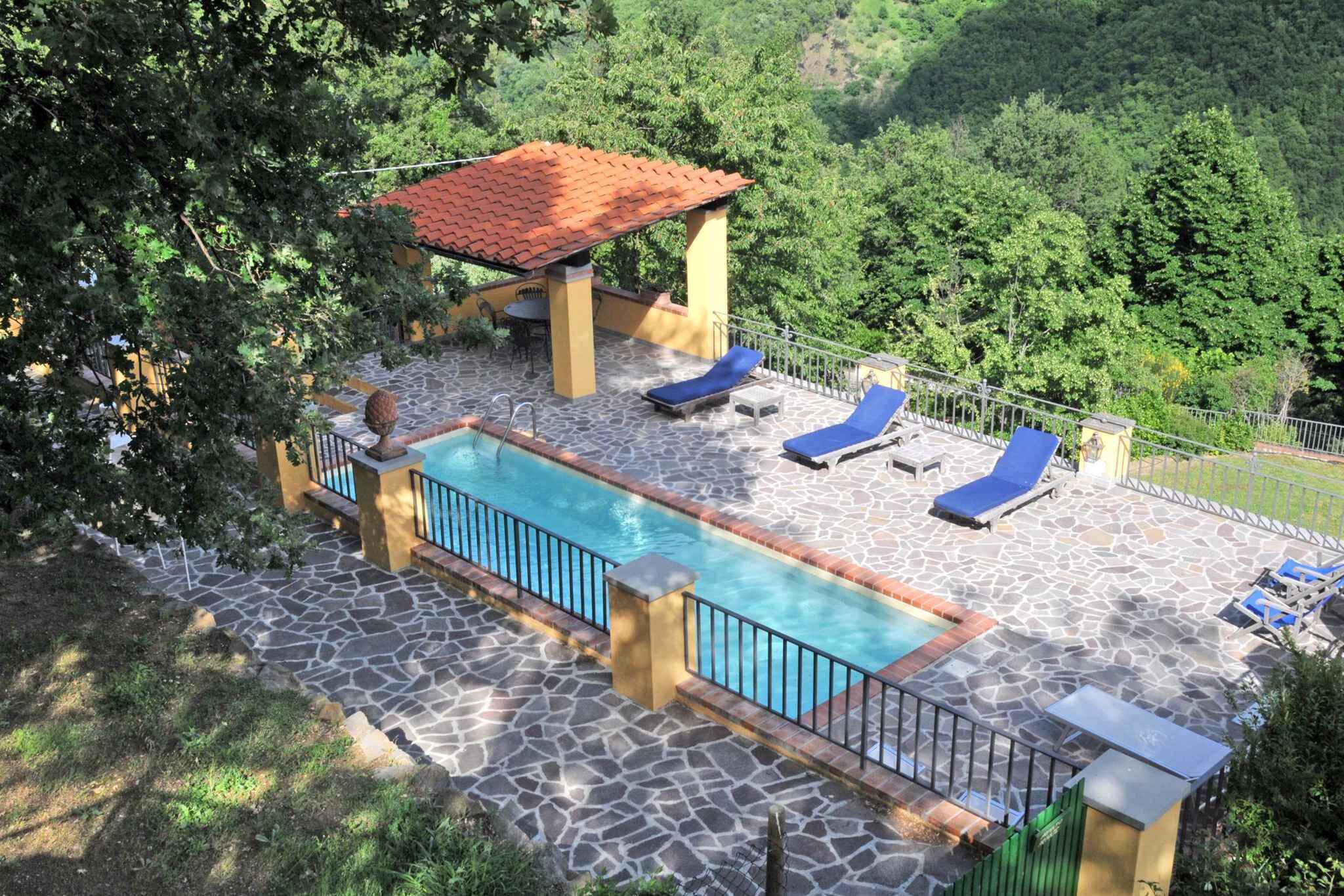 Un área de piscina con solárium empedrado, sillas de descanso y una pérgola.
