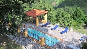 A pool area with a tiled deck, lounge chairs, and a pergola.