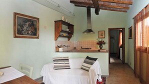 A cozy room with a bed, a wooden table, a kitchen area with a stove, and a hallway leading to another room.