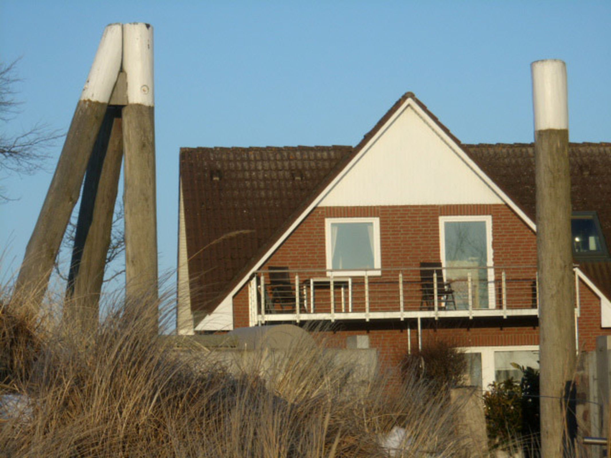 A two-story building with a brick facade, a white roof, and a balcony with railings.