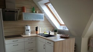 Eine Küche mit Backofen, Kaffeemaschine, Spüle und einer kleinen Topfpflanze.