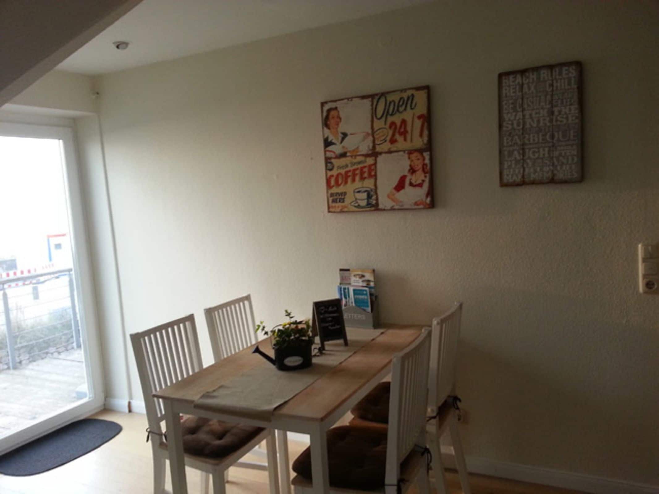 Un espace repas comprenant une table, des chaises, une machine à café et un tableau affichant le menu au mur.