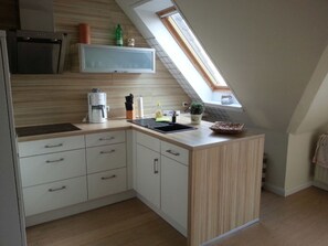 Eine Küche mit Backofen, Kaffeemaschine, Spüle und einer kleinen Topfpflanze.