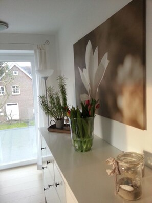 Eine moderne Küche mit einem großen Fenster, einem Blumentopf, einer Blumenvase und einem Bild an der Wand.