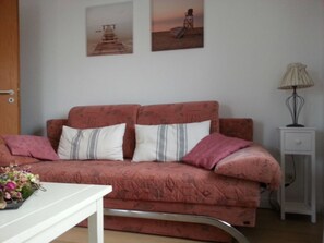 Une chambre à coucher avec un lit, une table de chevet, une lampe et deux tableaux accrochés au mur.