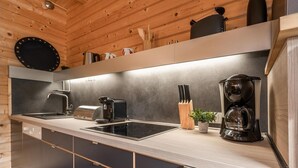 Eine moderne Küche mit Holzbalkendecke, einer schwarzen Kaffeemaschine, einem Wasserkocher und einem Messerblock.
