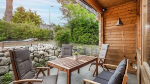 Eine Terrasse im Freien mit Holzmöbeln, einer Steinwand und Blick ins Grüne.