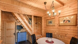 Ein Holzblockhaus-Innenraum mit Essbereich, Treppe und kleiner Küchenzeile.