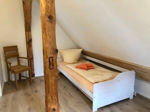 A small, single-bed room with a wooden chair and a white bed frame. - Captain's deck - vacation apartment in the captain's house (Wustrow)