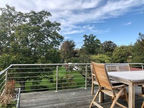 A wooden deck with a metal railing, a table, and a chair.