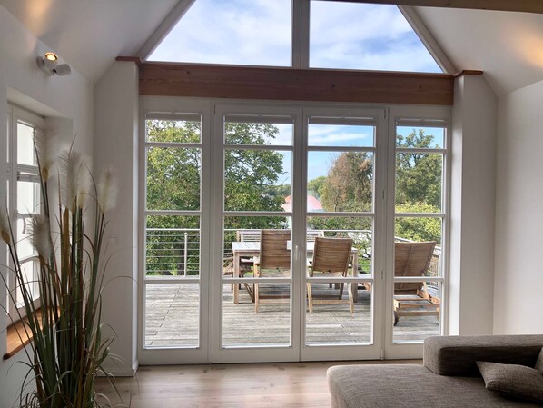 A room with a large sliding glass door leading to an outdoor deck with wooden furniture.