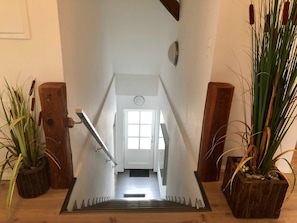 A staircase leading to a room with a white door, wooden handrails, and potted plants on either side. - Captain's deck - vacation apartment in the captain's house (Wustrow)