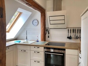 Een keuken met dakraam, een Siemens oven, witte kasten en een klok aan de muur.