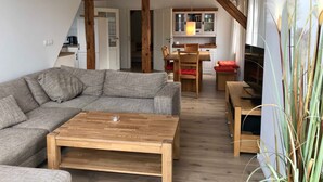 Una sala de estar con un sofá, una mesa de centro de madera y un comedor con mesa y sillas.