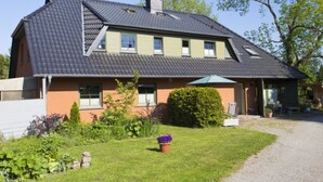A two-story house with a sloped roof, a front porch, and a well-maintained garden. - Vacation apartment Richard - Holiday home at the Museumshof (Zirkow)