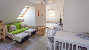A compact room with a green sofa, a small table, and a bed with star-patterned bedding. - Vacation apartment Richard - Holiday home at the Museumshof (Zirkow)