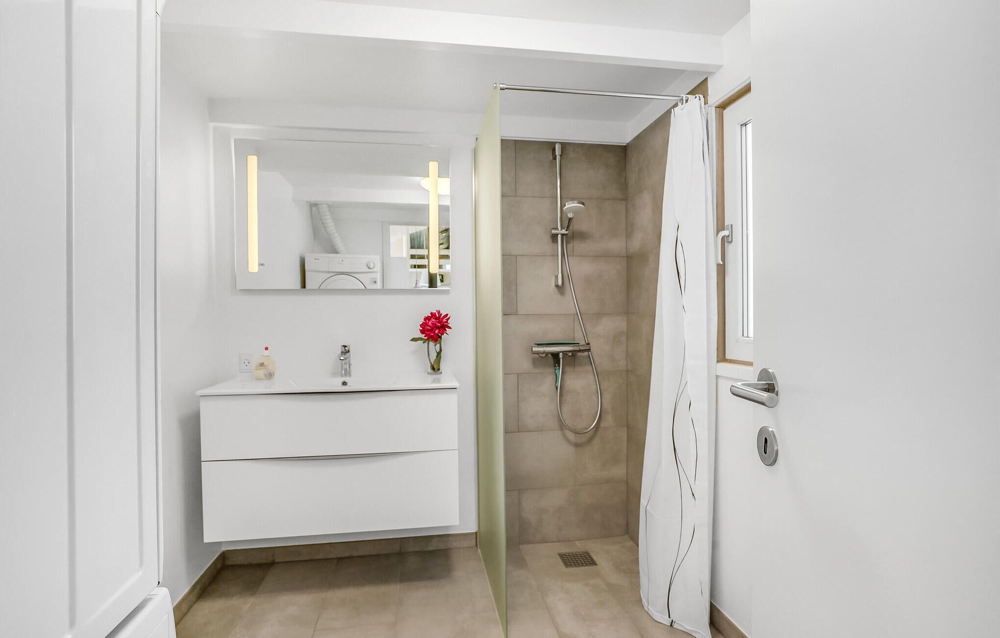 A modern bathroom with a white vanity, a mirror, a shower with a glass door, and a toilet.