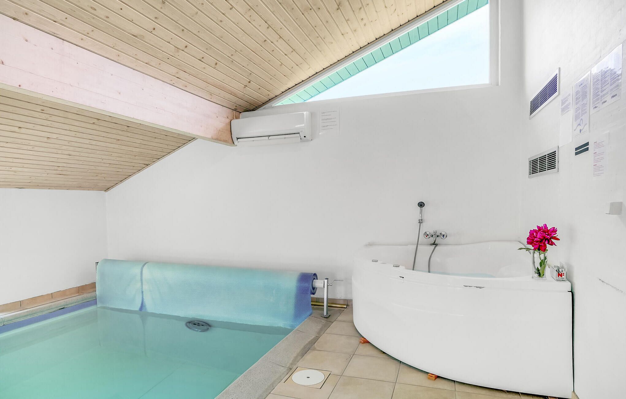 Een moderne badkamer met een inbouwhot tub, douche en een klein zwembad.