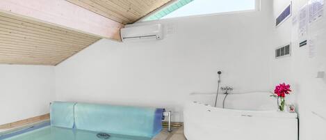 Een moderne badkamer met een inbouwhot tub, douche en een klein zwembad.