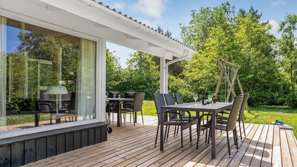 Eine Terrasss mit Tisch und Stühlen, einer Pergola und Blick ins grüne Umland.