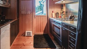 A compact kitchen with wooden walls, a stove, and a small window. - Gorgeous home in Sjusjøen with sauna (Sjusjøen)